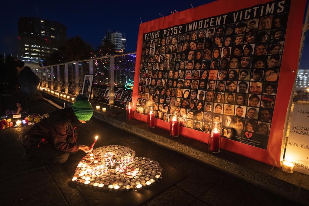 A mourner lights candles during a memorial for the anniversary of Flight PS752 in Edmonton on Friday, Jan. 8, 2021.