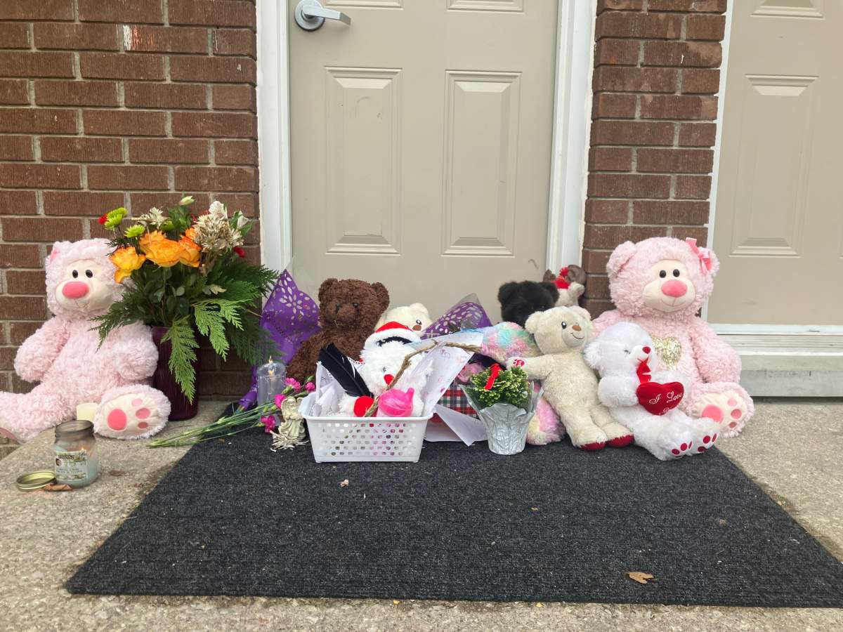 A memorial of flowers, candles, children’s drawings and stuffed teddy bears can be seen on the front steps of 416 Boulee St. as London, Ont., police investigate after two bodies were found in a townhouse complex on Saturday, Dec. 10, 2022.