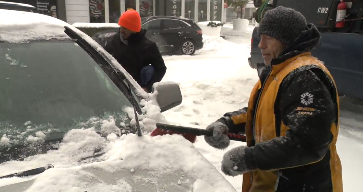 Motorists brush snow off their vehicle in Abbotsford, B.C. amidst a winter storm on Fri. Dec. 23, 2022.
