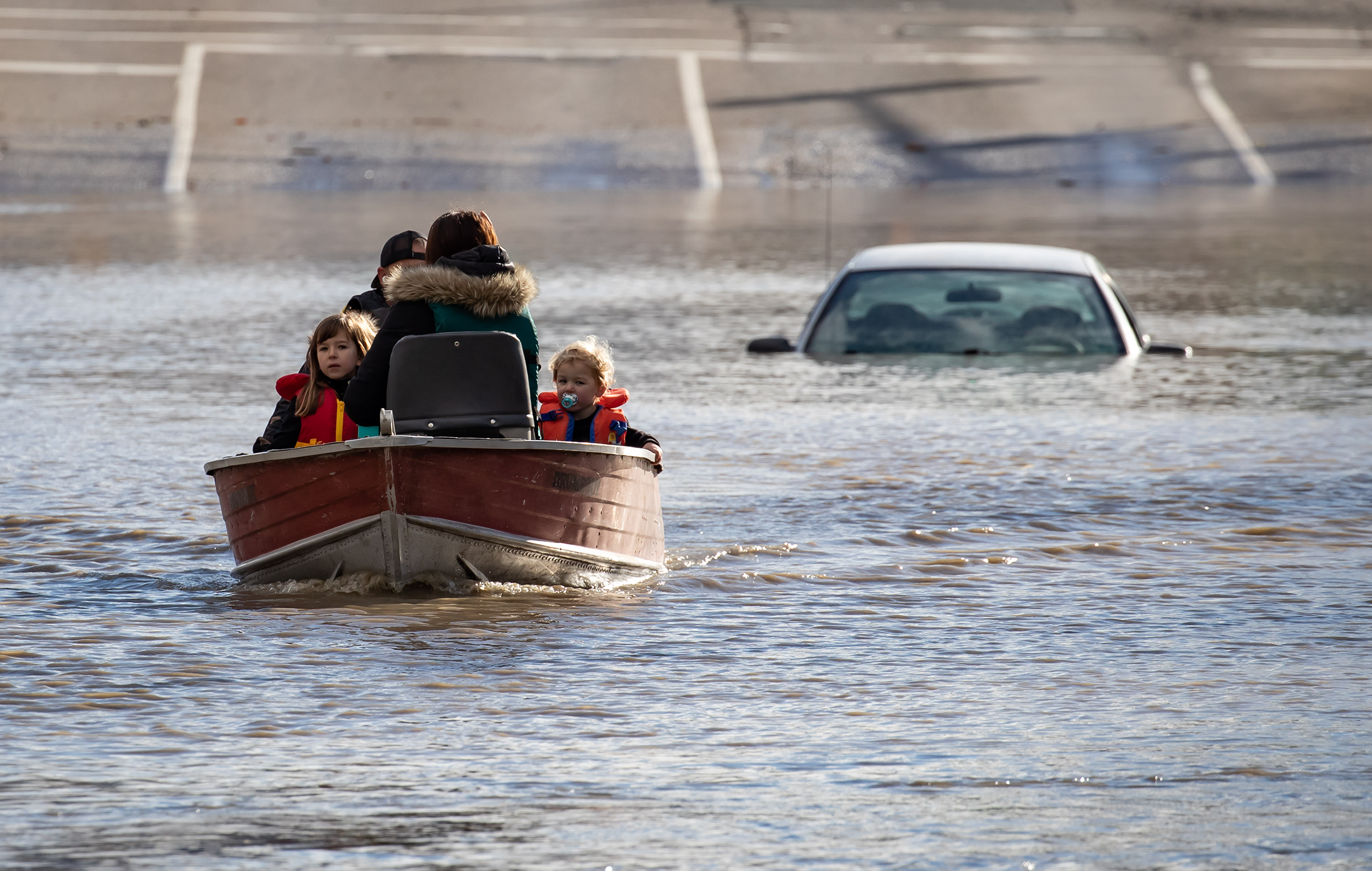 A family that was stranded by high water due to flooding is rescued by a volunteer operating a boat in Abbotsford, B.C., on Tuesday, November 16, 2021.