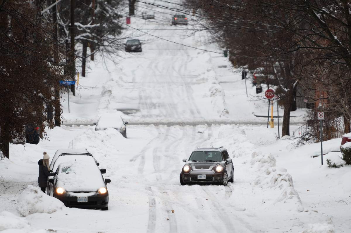A car sits stuck on a road in the Sandy Hill neighbourhood of Ottawa, on Friday, Dec. 23, 2022. Environment Canada has issued a winter storm warning for the region which is calling for flash freezing, icy and slippery surfaces, wind gusts and chills.