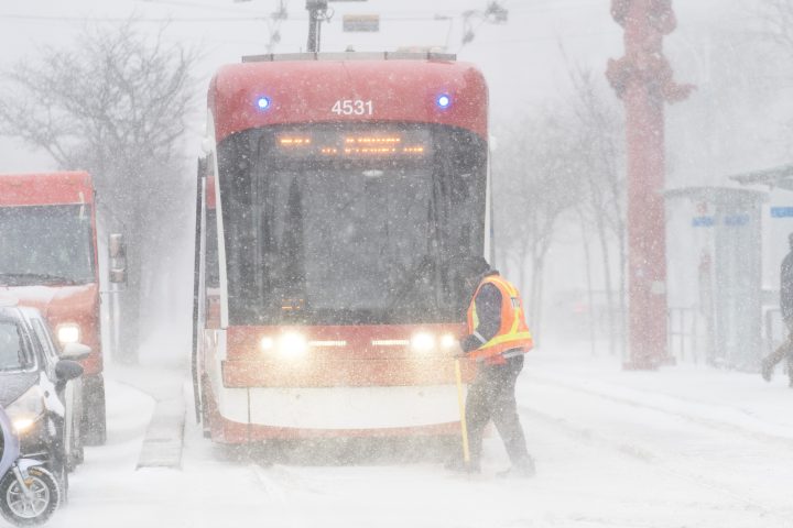 A streetcar driver works to clear ice from a track switch during a snowstorm in Toronto on Friday, December, 23, 2022.