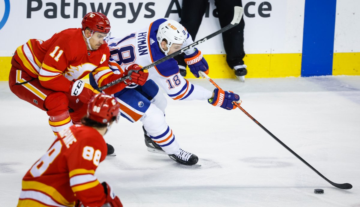 Edmonton Oilers forward Zach Hyman, right, steals the puck from Calgary Flames forward Mikael Backlund during first period NHL hockey action in Calgary, Tuesday, Dec. 27, 2022.