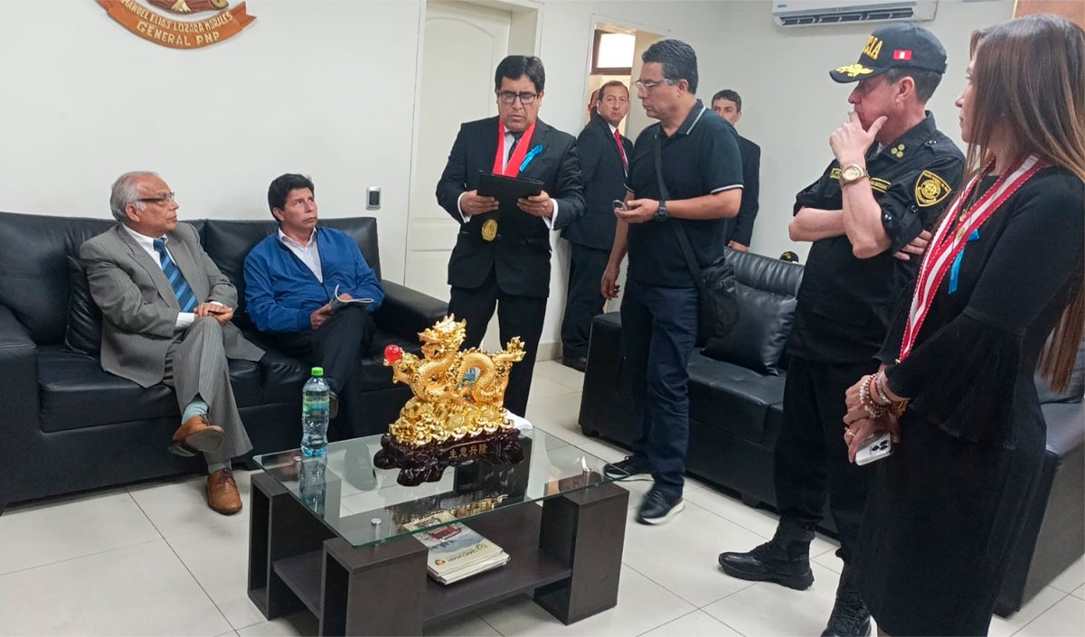 In this photo provided by Peru’s police administration office, former President Pedro Castillo, second from left, and former Prime Minister Anibal Torres, far left, sit as prosecutor Marco Huaman stands at center inside a police station, where Castillo and Torres’ status was not immediately clear, in Lima, Peru, Wednesday, Dec. 7, 2022. Peru’s Congress removed Castillo from office Wednesday and replaced him with the vice president, shortly after the president decreed the dissolution of the legislature ahead of a scheduled vote to oust him. (Peru’s police administration office via AP)