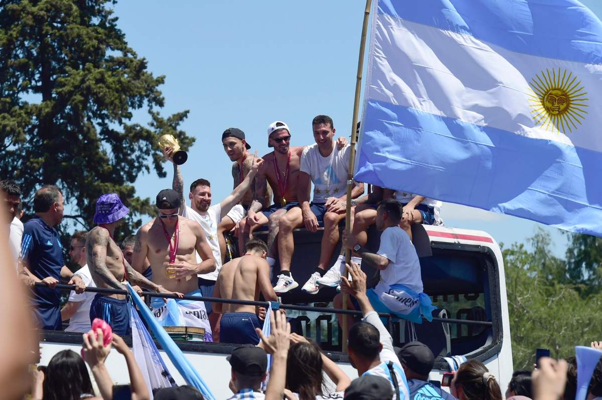 Lionel Messi raises the FIFA World Cup trophy as he rides on an open-top bus with teammates of the Argentine soccer team that won the World Cup tournament in Buenos Aires, Argentina, Tuesday, Dec. 20, 2022. (AP Photo/Julio Ruiz)