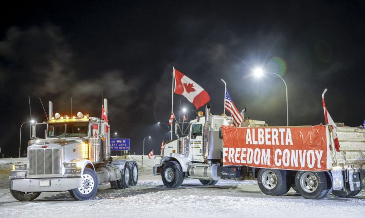 Anti-COVID-19 vaccine mandate demonstrators gather as a truck convoy blocks the highway at the busy U.S. border crossing in Coutts, Alta., Tuesday, Feb. 1, 2022.