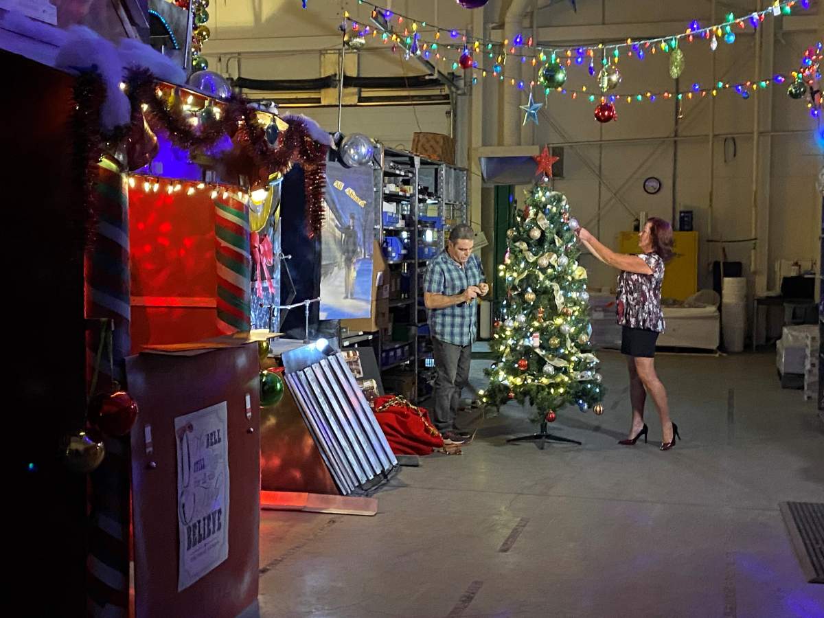 Two people decorate a Christmas tree in an ATCO warehouse