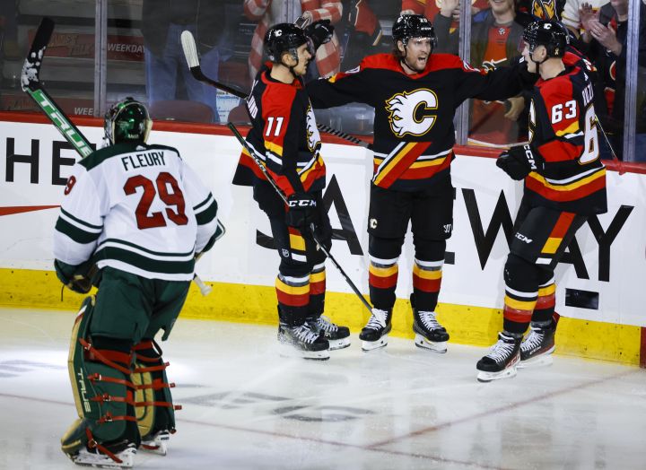 Minnesota Wild goalie Marc-Andre Fleury, left, skates away as Calgary Flames forward Blake Coleman, centre right, celebrates his goal with teammates during second period NHL hockey action in Calgary, Wednesday, Dec. 7, 2022.