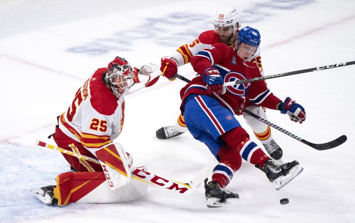 Montreal Canadiens’ Christian Dvorak (28) is taken out from in front of Calgary Flames goaltender Jacob Markstrom by Flames defenceman Noah Hanifin during first period NHL hockey action in Montreal, Monday, Dec. 12, 2022.