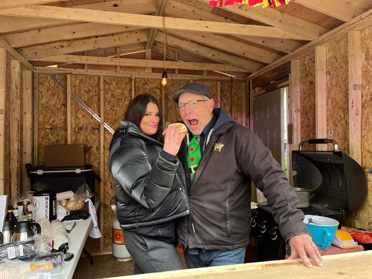 Chris Lyons of Chris’ Country Cuts takes a bite out of a peameal bacon sandwich served by Olive R. Twists’ Madigan Davies.