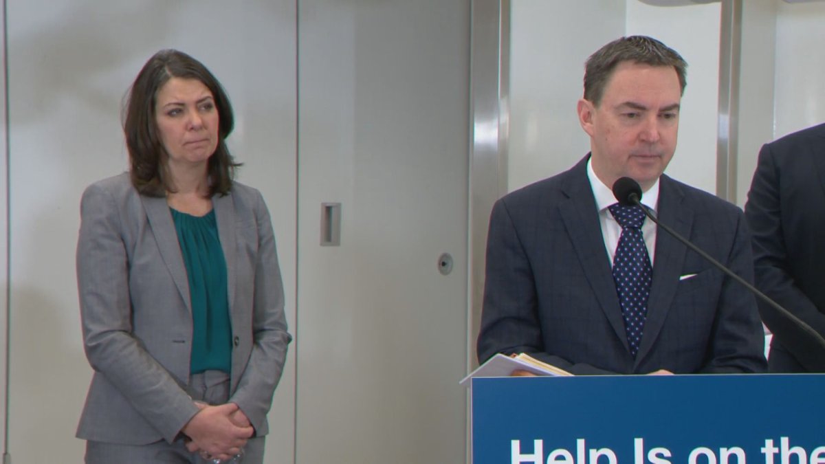 Alberta Premier Danielle Smith (L) looks on as Health Minister Jason Copping speaks at a press conference on Dec. 21, 2022.