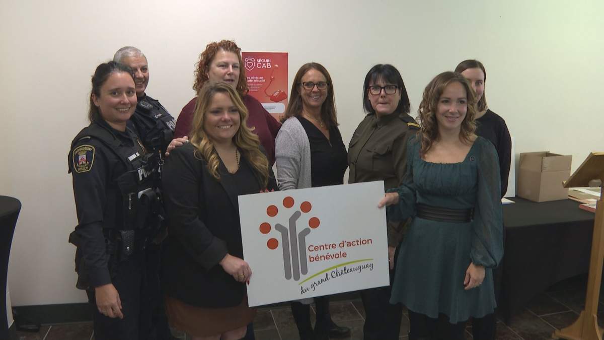 Centre D'Action Bénévole members pose with poster at announcement. 