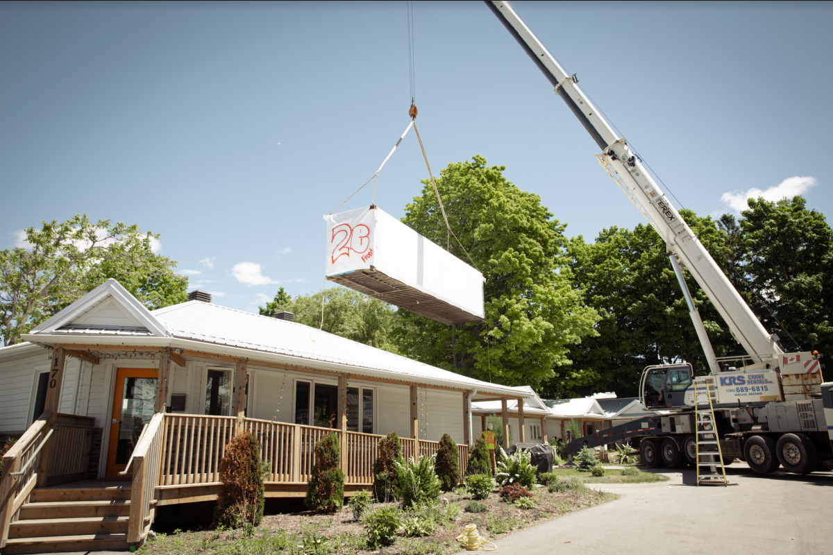 Crane moving shipping container for Lucy's Place expansion in Barrie, Ont.