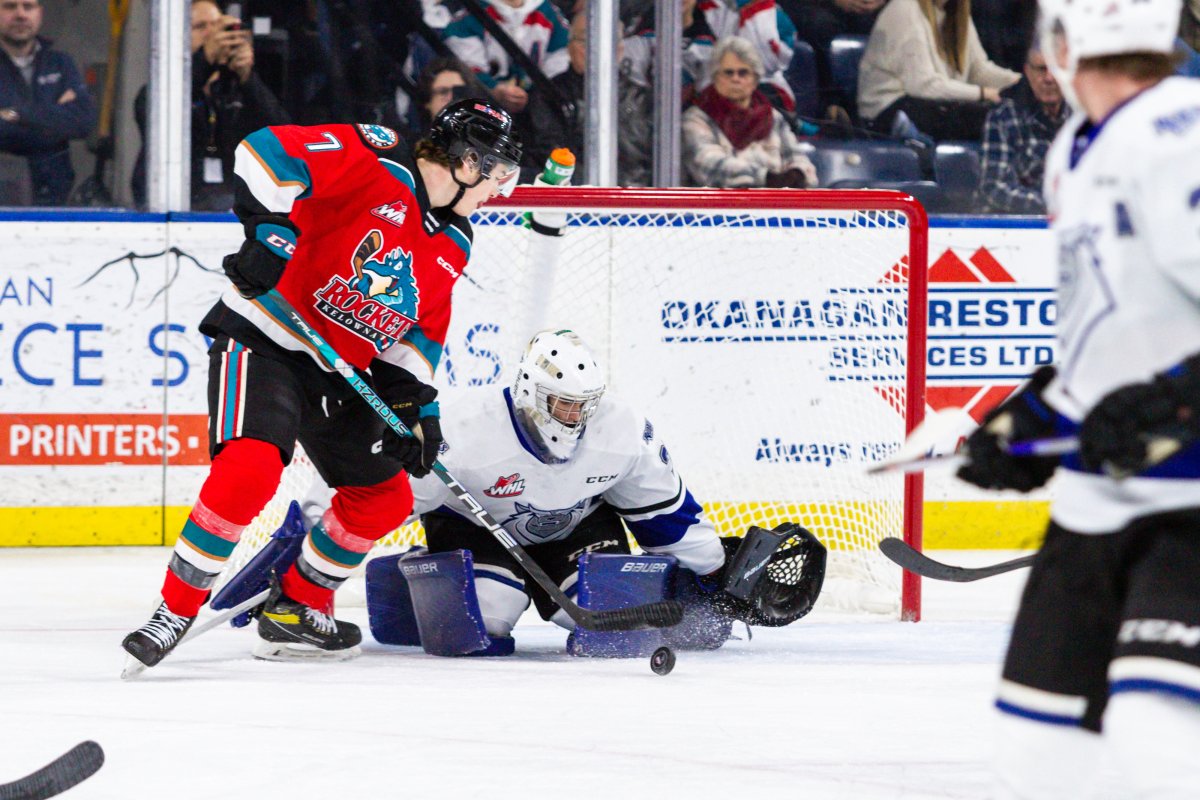 Kelowna Rockets centre Max Graham, left, and Victoria Royals goalie Nicholas Cristiano both eye the puck during WHL action at Prospera Place in Kelowna, B.C., on Friday, Dec. 9, 2022. Victoria won 3-2.