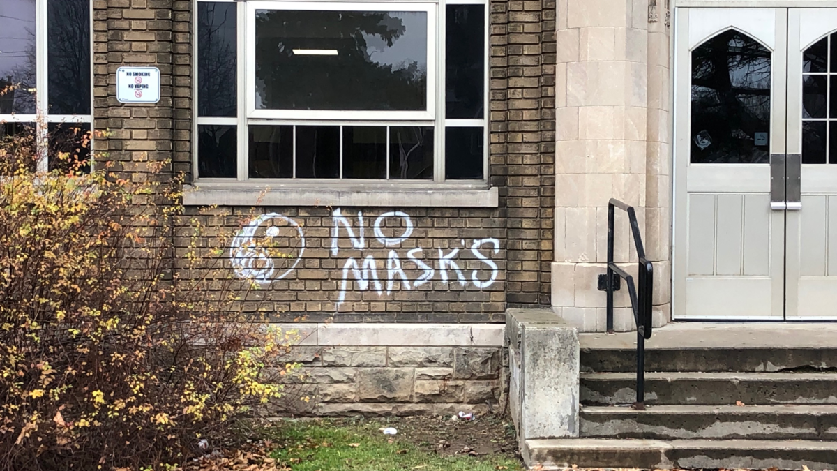 Graffiti that says "NO MASKS" on the outside of Westdale Secondary School.