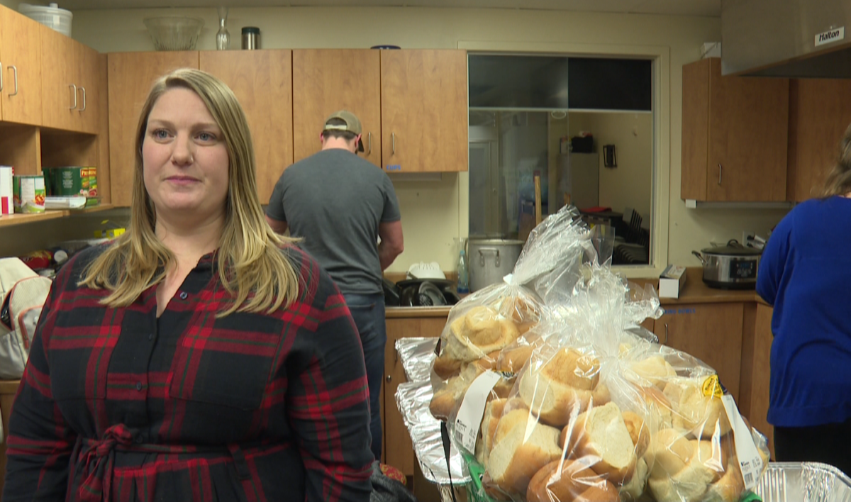 Ashton Beardsworth stands in a small kitchen as volunteers prepare food behind her.