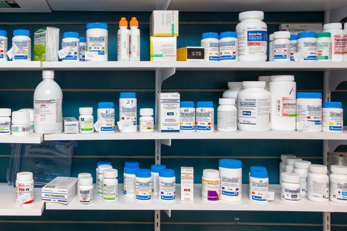A pharmacy shelf is stocked with prescription medication bottles.