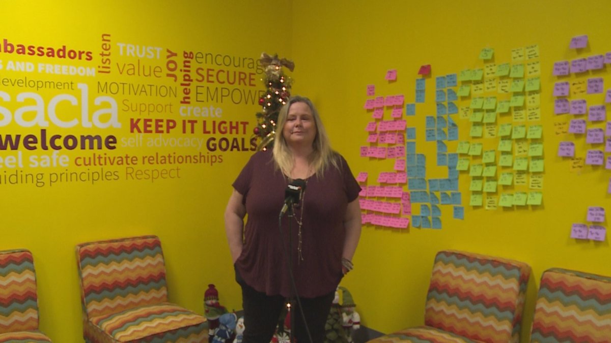 Heather Caldwell, who works at the Southern Alberta Community Living Association (SACLA), stands in front of a wall filled with sticky notes. The notes represent shifts the organization still needs to fill in December and January. 