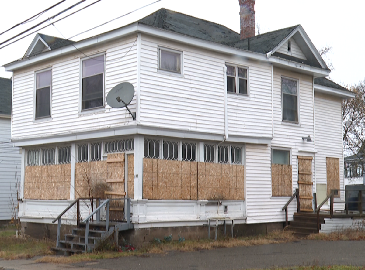 A white, 1930s era house sits boarded up on a Moncton street.
