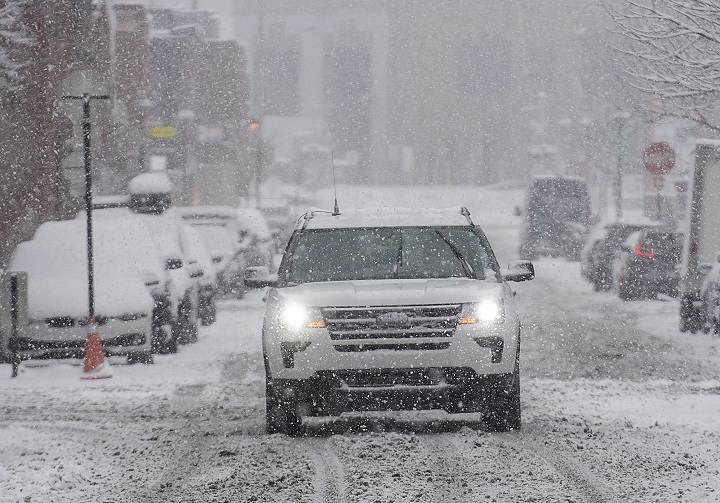 A car makes its way along a snow covered street in Montreal, Wednesday, Nov. 16, 2022, as the first major snowfall hits the city.