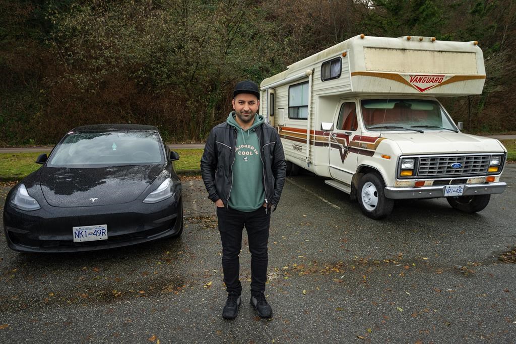 Lucas Philips is pictured outside his camper and next to his Tesla in a parking lot where he has been living at Spanish Banks, in Vancouver, B.C., Thursday, Dec. 8, 2022. Philips is part of Metro Vancouver's camper community, some living on wheels as an economic strategy, some as a lifestyle choice and others as a last resort. THE CANADIAN PRESS/Jonathan Hayward.