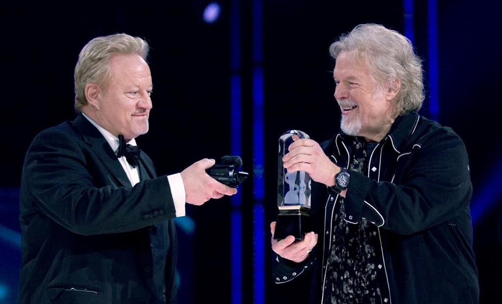 Randy Bachman (right) holds the Juno as Robbie Bachman videotapes a closeup of the trophy after being inducted into the Canadian Music Hall of Fame at the Juno Awards in Winnipeg, Sunday, March 30, 2014.