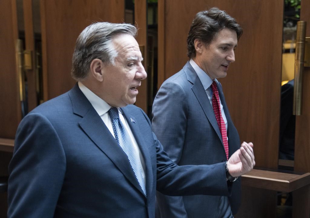 Prime Minister Justin Trudeau and Quebec Premier Francois Legault chat while walking to a meeting in Montreal on December 20, 2022. Quebec's police watchdog is investigating after a member of a provincial police tactical team shot a man suspected of making threats toward the premier and prime minister.