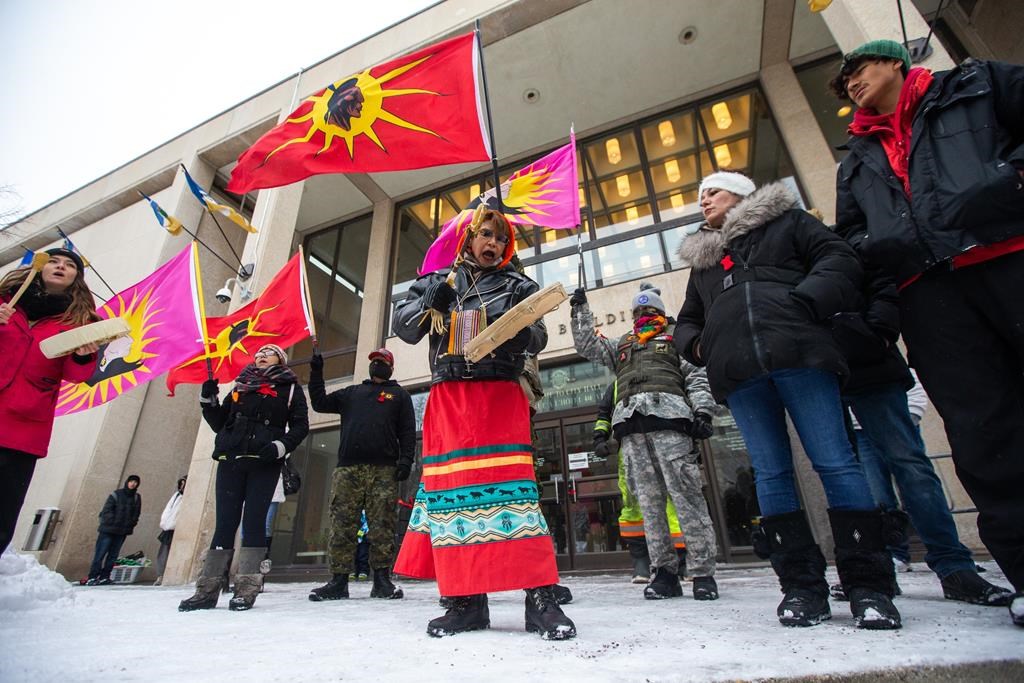 Sue Caribou, centre, sings a song in front of Winnipeg city hall during a rally, Thursday, Dec. 15, 2022, to call on the city to cease dumping operations at Brady landfill and conduct a search for the remains of missing and murdered indigenous women believed to be buried there.