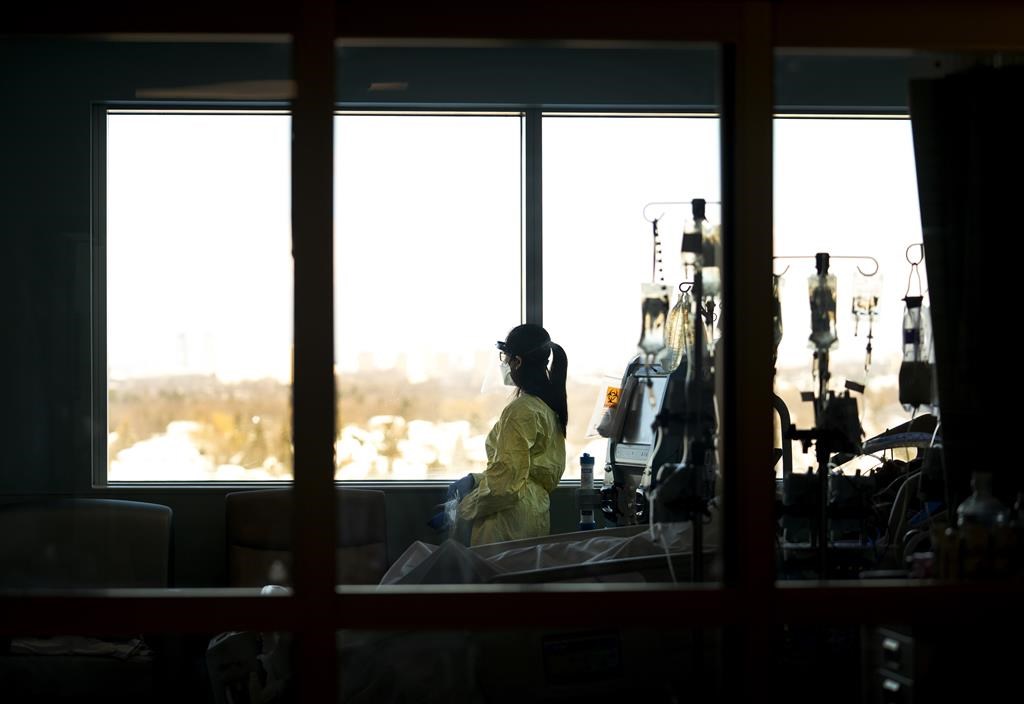 A registered nurse takes a moment to look outside while attending to a patient in the intensive care unit at the Humber River Hospital in Toronto on Tuesday, Jan. 25, 2022. 