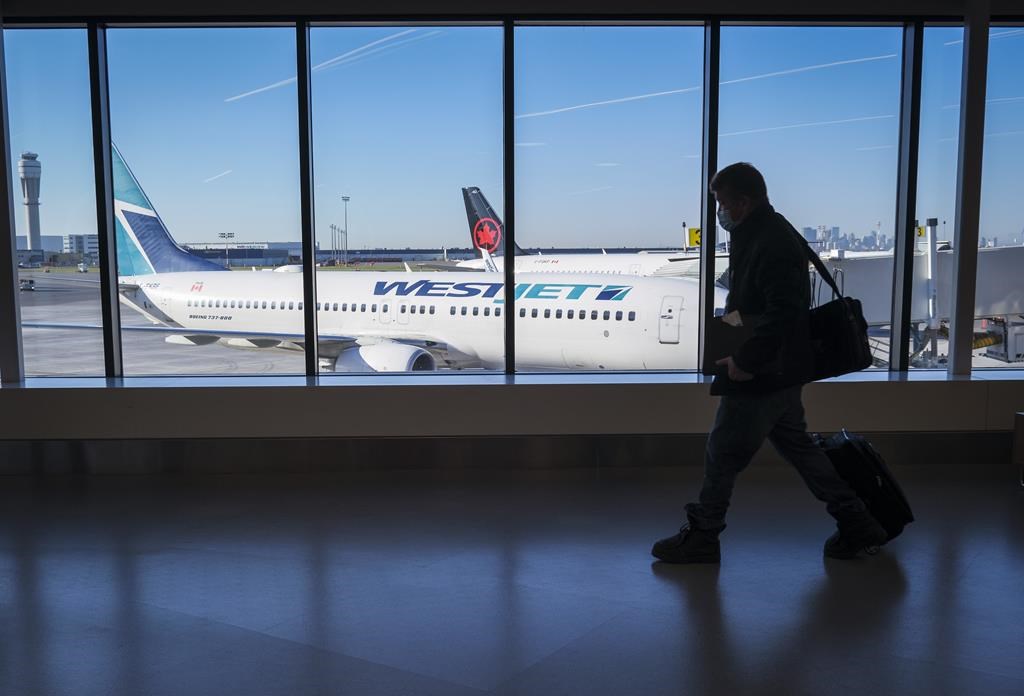 FILE. Passengers walk past Air Canada and WestJet planes at Calgary International Airport in Calgary, Alta., Wednesday, Aug. 31, 2022.