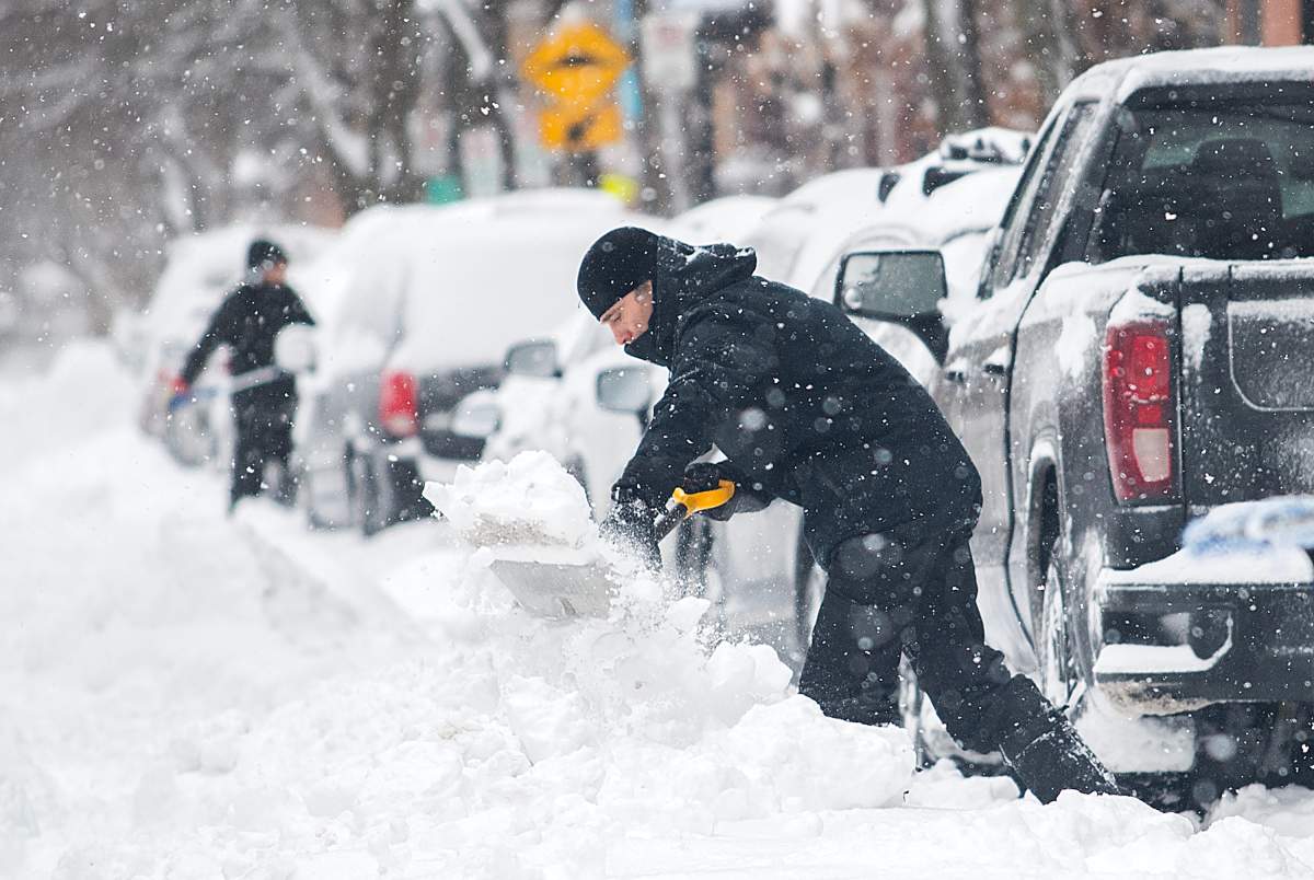 People clear snow from around their vehicles during a snowstorm in Montreal, Thursday, January 26, 2023.