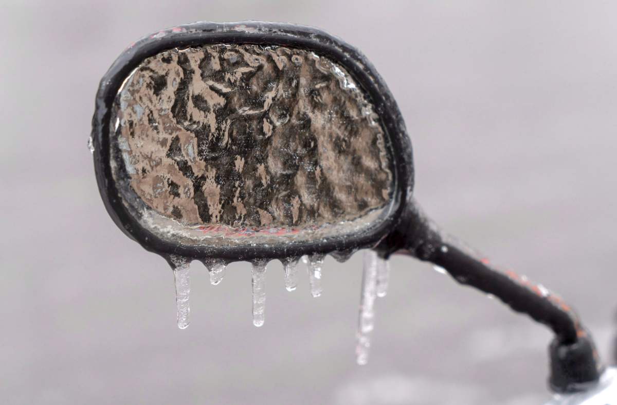 The ice-covered mirror of a motorcycle is seen following freezing rain Monday, April 16, 2018.
