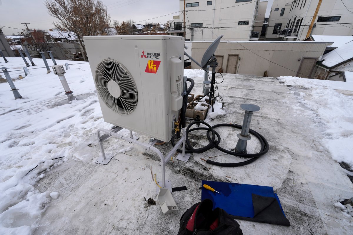 A condenser sits on the roof during the installation of a heat pump in an 80-year-old rowhouse Friday, Jan. 20, 2023, in northwest Denver.