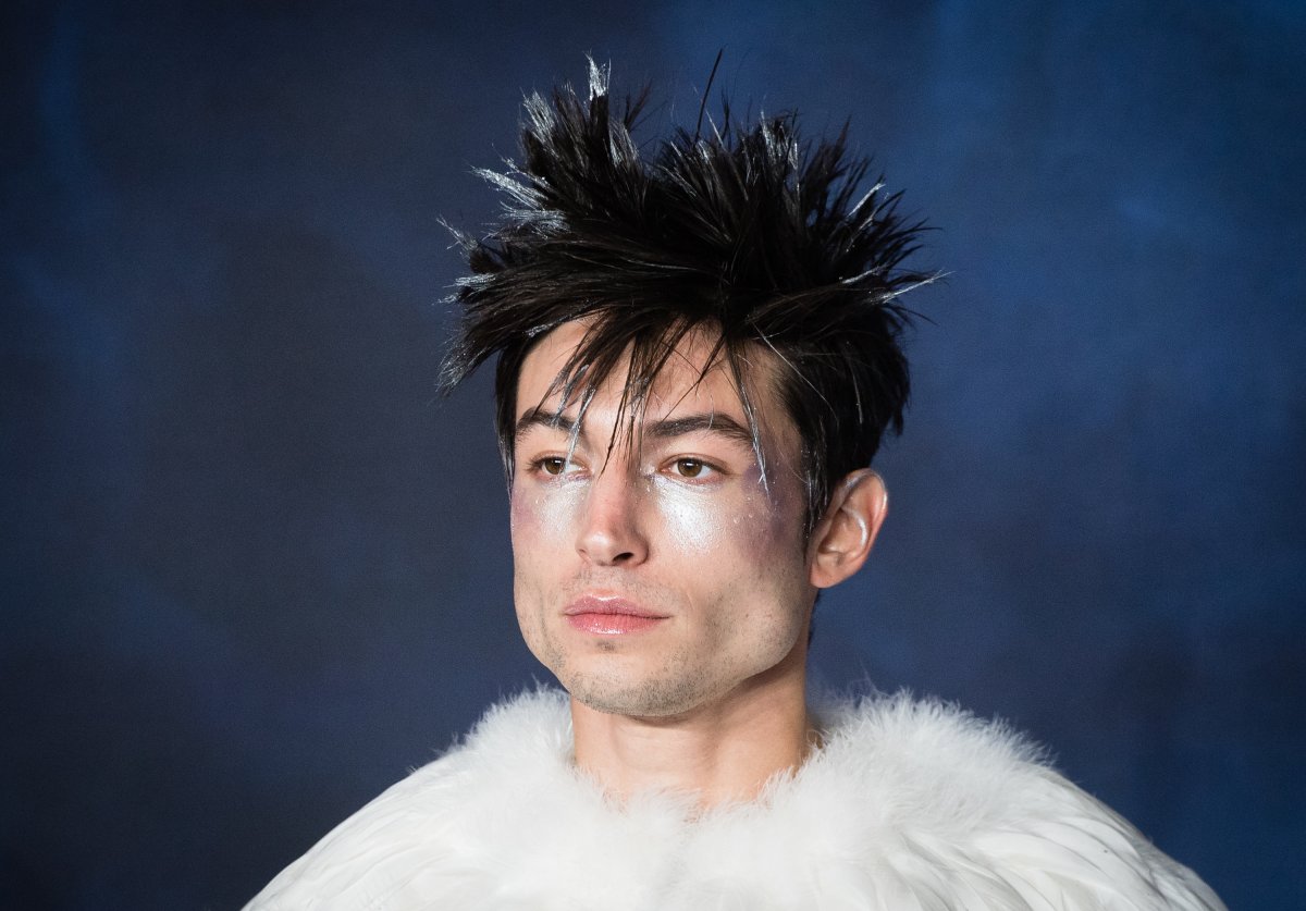 Ezra Miller. Their hair is spiked and frosted white at the tips. They are wearing silver glitter on their face.