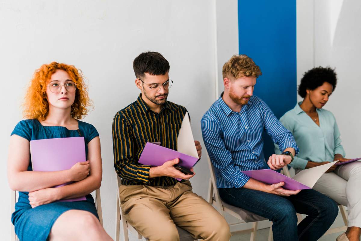 A stock photo shows a large group of people sitting in waiting room before job interview for their potential business position.
