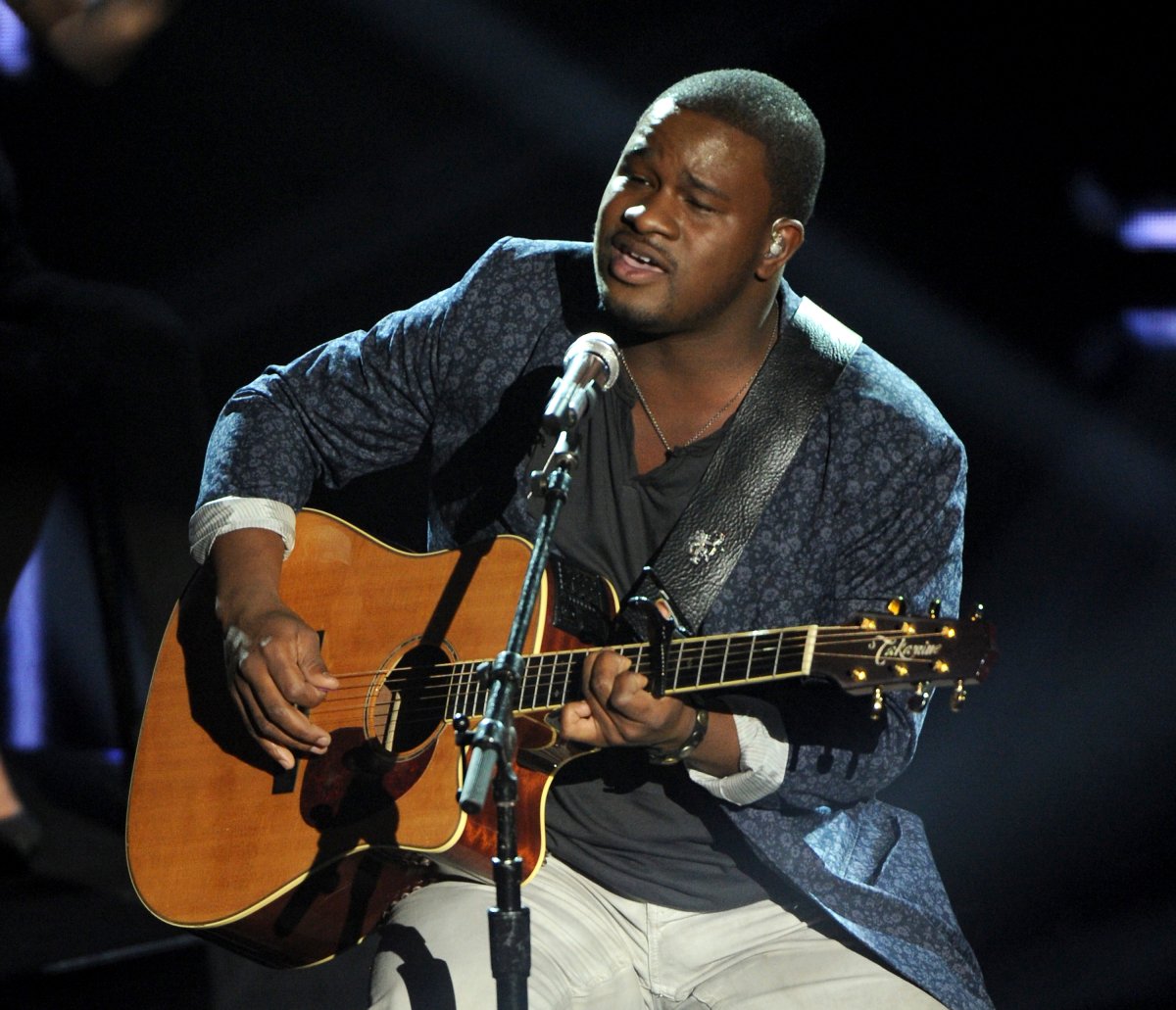 C.J. Harris on stage with a guitar. He is singing into a microphone.