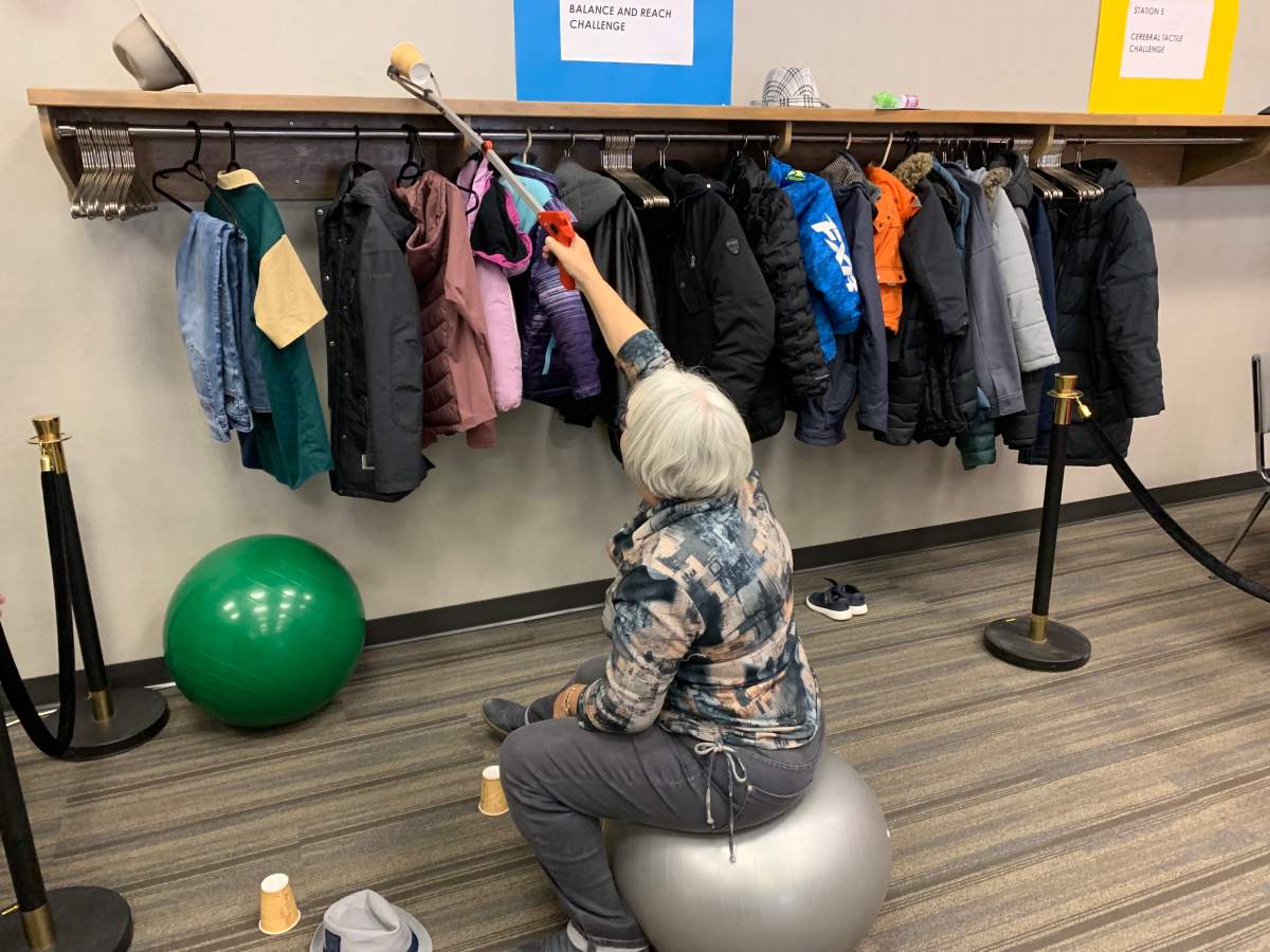 Attendee tries to grab cups from high shelf using an ‘adapted device’.