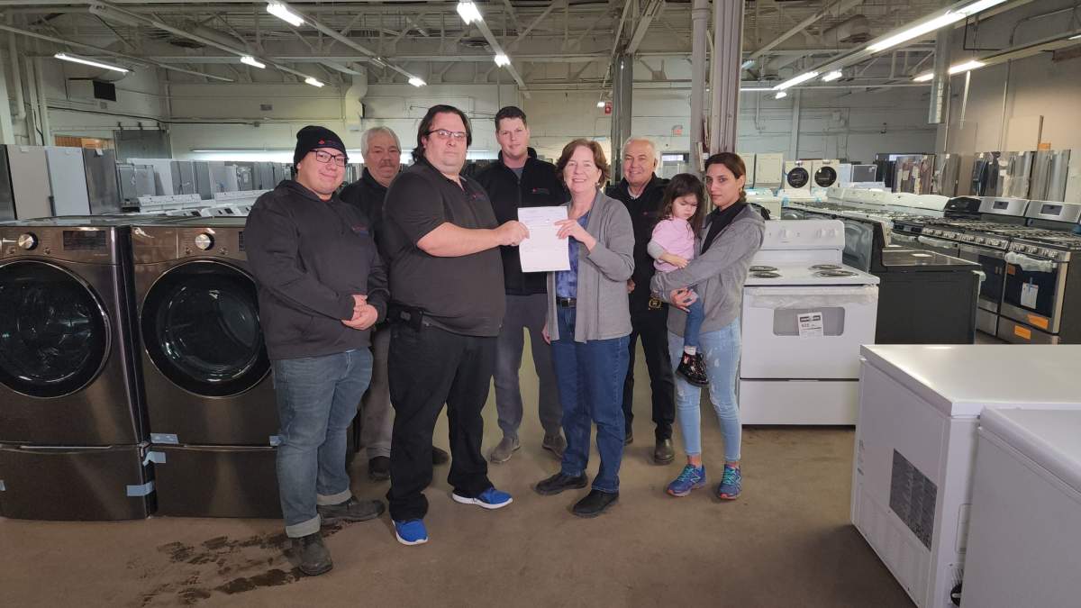 Officials with London Direct Liquidation and Indwell gather inside the east London, Ont., appliance store for Friday's cheque presentation.