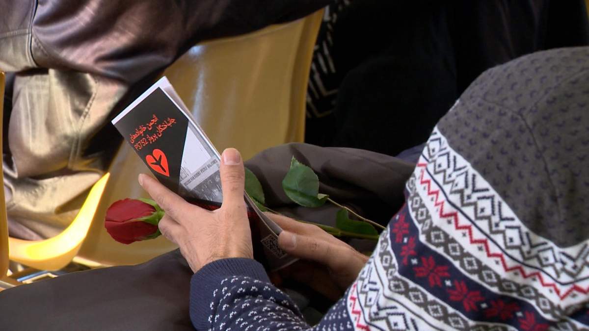 A Saskatoon resident can be seen holding a rose during a ceremony mourning those who lost their life on Flight 752.