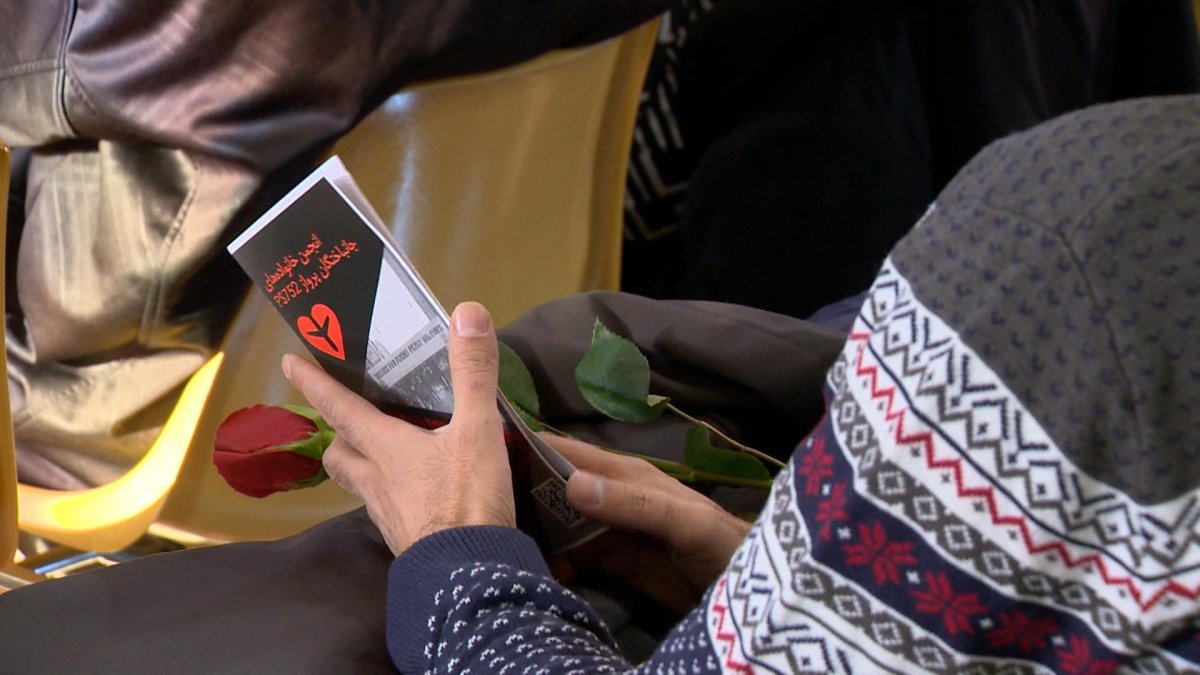 A Saskatoon resident can be seen holding a rose during a ceremony mourning those who lost their life on Flight 752.