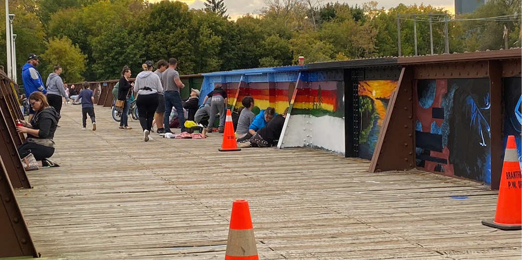 A photo of volunteers working on the interior panels of the TH&B Crossing Bridge art project in Brantford, Ont.