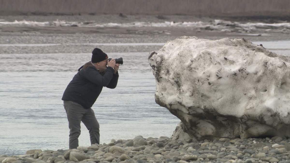 A man takes a photo of one of the huge ice chunks washed up along the banks of the Fraser River.