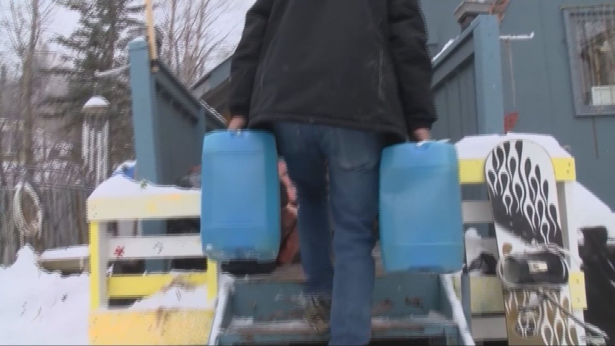 A lakeview Trailer Park resident carries water into his home.