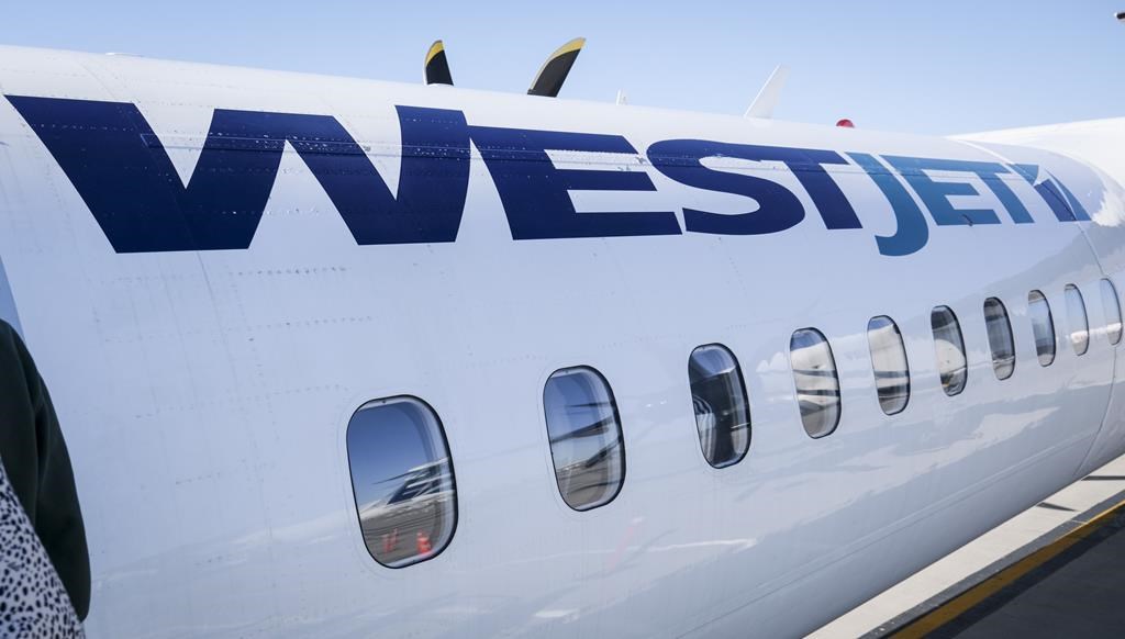 A WestJet plane waits at a gate at Calgary International Airport in Calgary, Alta., Wednesday, Aug. 31, 2022. The union representing WestJet pilots says contract negotiations with the airline have been unproductive and federal arbitration may be needed to avert a strike.