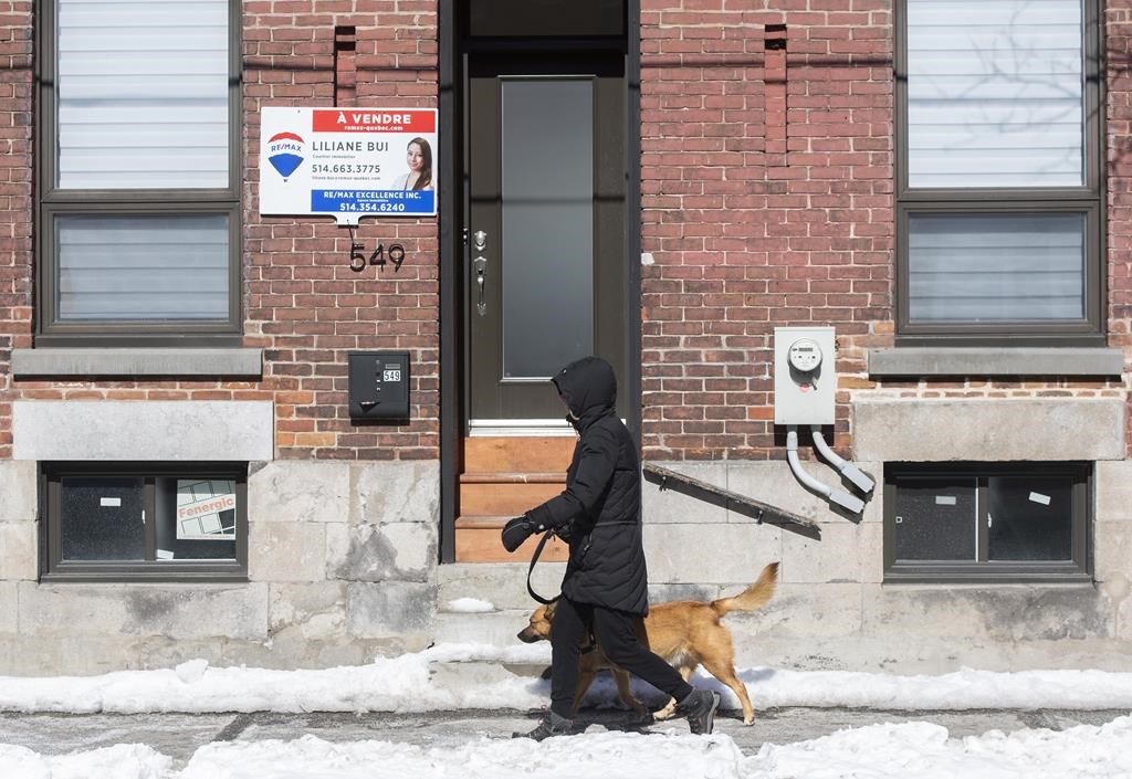 The Quebec Professional Association of Real Estate Brokers says Montreal's January home sales fell to a level not seen since 2009 as the market slowdown continued. A woman walks by a house for sale in Montreal, Friday, March 4, 2022. 