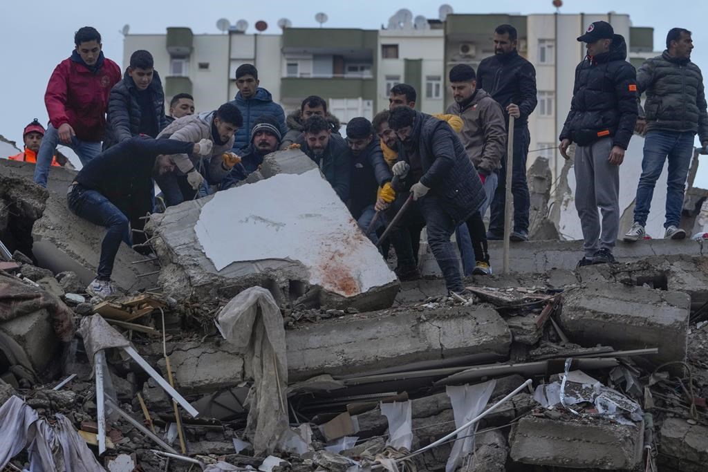 Men search for people among the debris in a destroyed building in Adana, Turkey, Monday, Feb. 6, 2023.