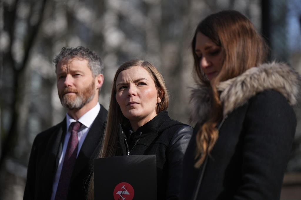 Photojournalist Amber Bracken, centre, lawyer Sean Hern, back left, and Emma Gilchrist, editor-in-chief and executive director of The Narwhal, listen during a news conference after filing a lawsuit at B.C. Supreme Court against the RCMP, in Vancouver, on Monday, Feb. 13, 2023. Bracken was arrested and detained while covering the enforcement of an injunction in Wet'suwet'en territory as a journalist in 2021. 