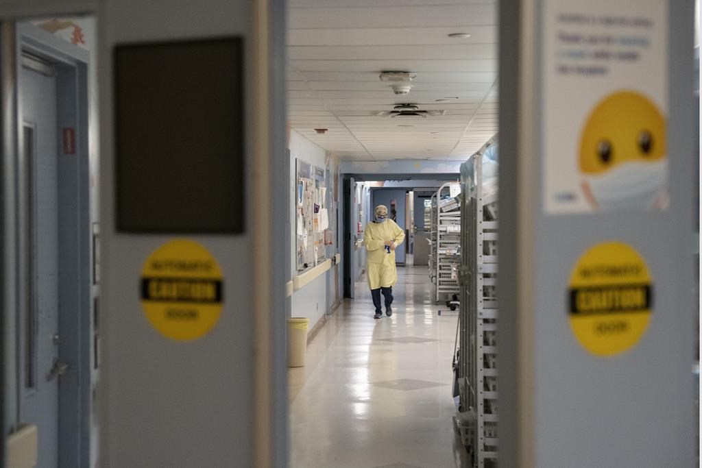 A health-care worker in the distance of a hospital hallway.