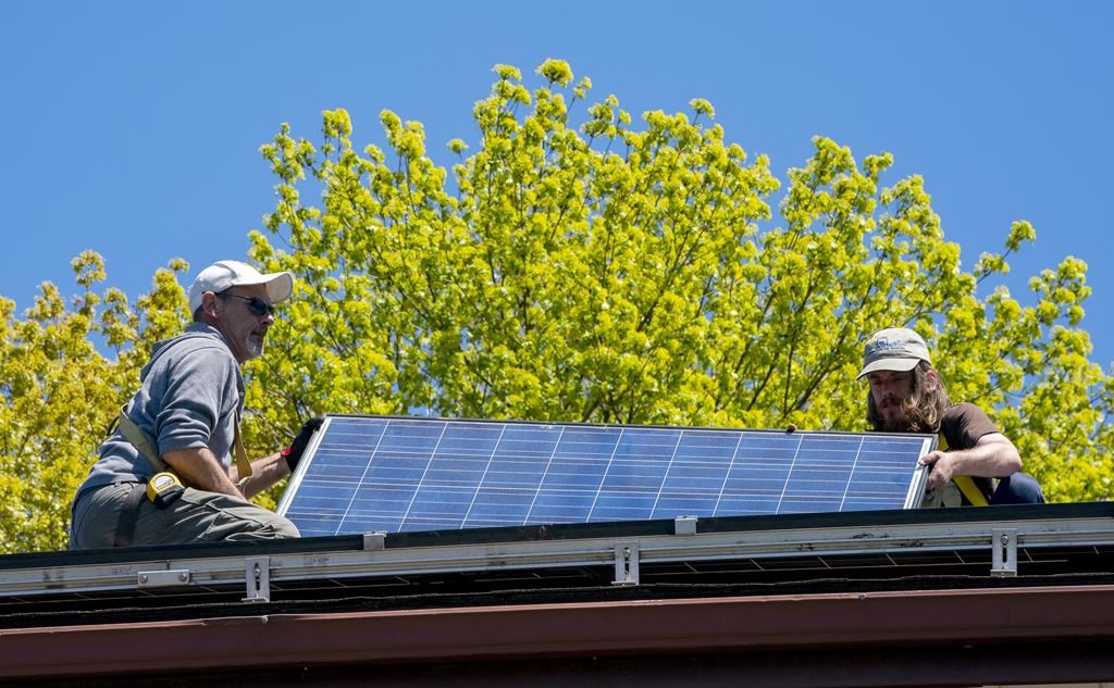 Solar installers Derek Craig, left, and Dave Osborne install solar panels on a roof in Toronto on Wednesday, May 12, 2021. The latest edition of the TSX Venture 50 list shows investors are increasingly snapping up stocks with any sort of "energy transition" theme. 