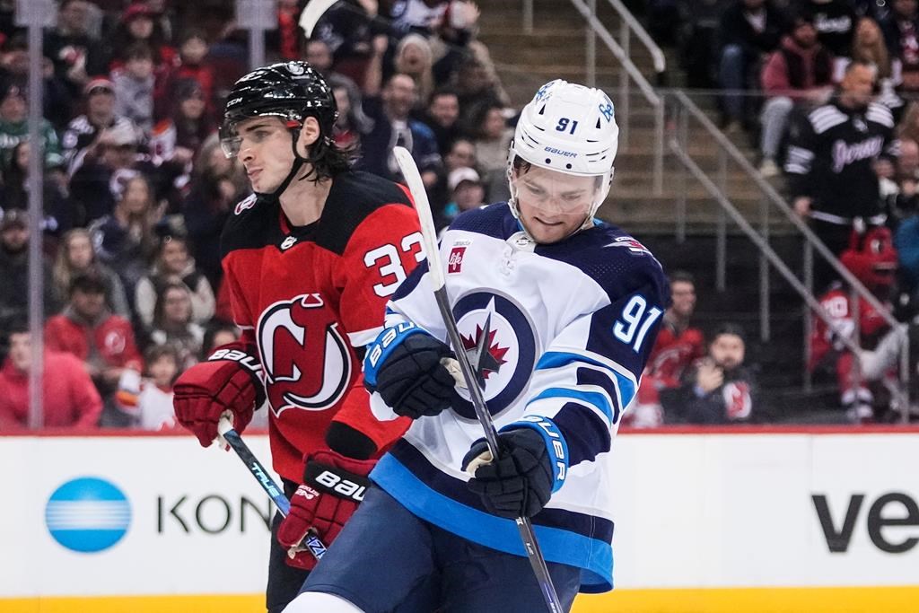 Winnipeg Jets’ Cole Perfetti (91) celebrates a goal while skating past New Jersey Devils’ Ryan Graves (33) during a game in Newark, N.J., on Feb. 19, 2023.